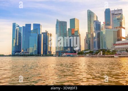 Abend Singapur. Wolkenkratzer am Ufer der Marina Bay. Die Sonne färbte das Wasser golden Stockfoto