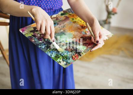 Künstler Pinsel und Ölfarben auf Holzpalette. Makrokünstler-Palette, Textur gemischte Ölfarben in verschiedenen Farben und Sättigung. Palette mit PA Stockfoto