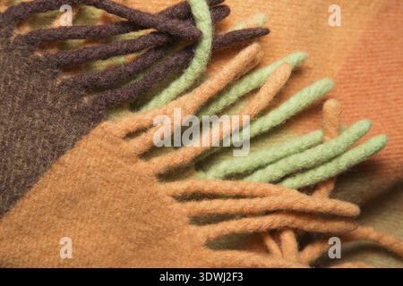 Weiche und warme gefaltete Alpaka-Wolldecke mit Fransen. Grün und orange Wolle karierten Textur Makro Schuss. Wolle karierter Stoff mit Fransen. Wolldecke Stockfoto