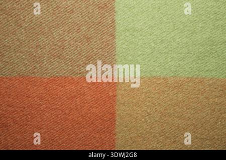 Weiche und warme gefaltete Alpaka-Wolldecke. Grün und orange Wolle karierten Textur Makro Schuss. Wolldecke mit Karomuster Wolldecke Stockfoto