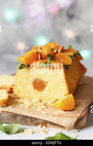 Orange Pound Cake mit frisch gepresstem Orangensaft und Schale, dekoriert mit getrockneten Aprikosen, Minzblättern und Mandeln Stockfoto