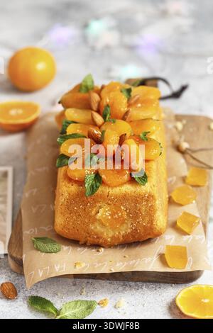Orange Pound Cake mit frisch gepresstem Orangensaft und Schale, dekoriert mit getrockneten Aprikosen, Minzblättern und Mandeln Stockfoto
