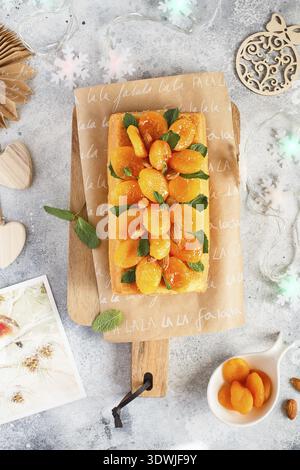 Orange Pound Cake mit frisch gepresstem Orangensaft und Schale, dekoriert mit getrockneten Aprikosen, Minzblättern und Mandeln Stockfoto
