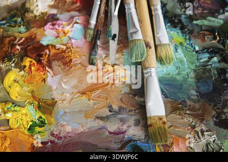 Künstler Pinsel und Ölfarben auf Holzpalette. Makrokünstler-Palette, Textur gemischte Ölfarben in verschiedenen Farben und Sättigung. Palette mit PA Stockfoto