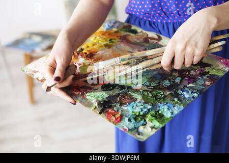 Künstler Pinsel und Ölfarben auf Holzpalette. Makrokünstler-Palette, Textur gemischte Ölfarben in verschiedenen Farben und Sättigung. Palette mit PA Stockfoto