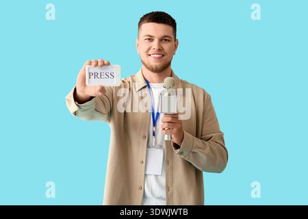 Männlicher Reporter mit Mikrofon und DRUCKABZEICHEN auf blauem Hintergrund Stockfoto