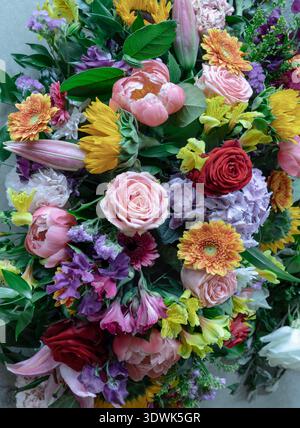 Dieser üppige Blumenstrauß besticht durch seine farbenprächtigen Rosen in tiefrotem und zartem Rosa und einer voluminösen Hortensie, während die leuchtend orange Gerbera in Gänseblümchen fällt Stockfoto