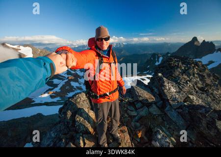 Zwei Bergsteiger schlagen mit der Faust, nachdem sie den Gipfel des Stewart Peak erreicht haben. Stockfoto