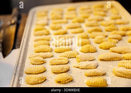 Traditionelle italienische Nudelknödel sind in sauberen Linien auf einem Backblech angeordnet. Die ungekochten Gnocchi weisen eine charakteristische geriffelte Textur auf und sind li Stockfoto