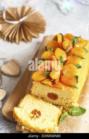 Orange Pound Cake mit frisch gepresstem Orangensaft und Schale, dekoriert mit getrockneten Aprikosen, Minzblättern und Mandeln Stockfoto
