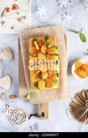 Orange Pound Cake mit frisch gepresstem Orangensaft und Schale, dekoriert mit getrockneten Aprikosen, Minzblättern und Mandeln Stockfoto