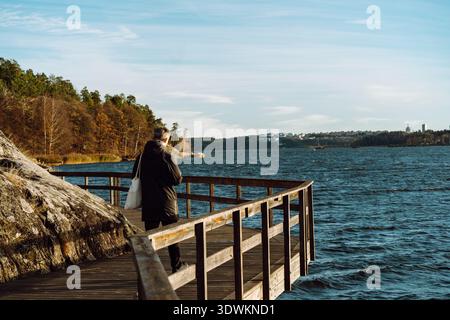 Mann, der auf einer hölzernen Promenade steht und auf den See blickt Stockfoto