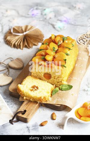 Orange Pound Cake mit frisch gepresstem Orangensaft und Schale, dekoriert mit getrockneten Aprikosen, Minzblättern und Mandeln Stockfoto