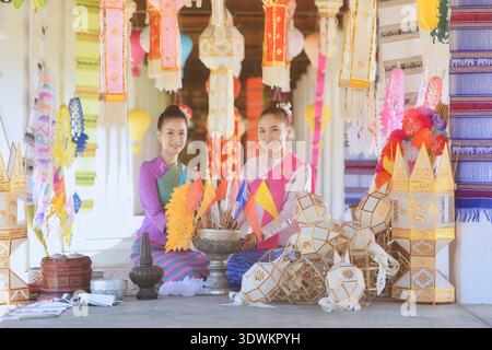 Zwei junge Frauen in traditioneller Lanna Thai Kleidung sitzen vor einem Tempel, Wat Intharawat, Chiang Mai, Thailand Stockfoto