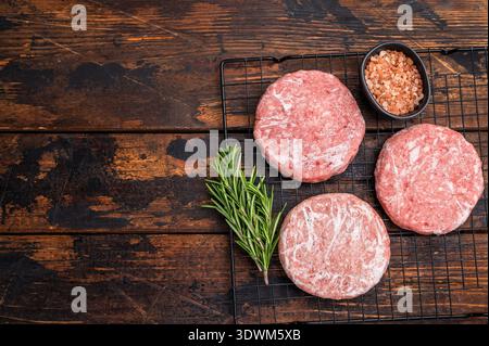 Gefrorene Fleischpasteten, bereit zum Grillen, Forcemeat von Schwein und Rindfleisch für Burger. Hölzerner Hintergrund. Draufsicht. Stockfoto