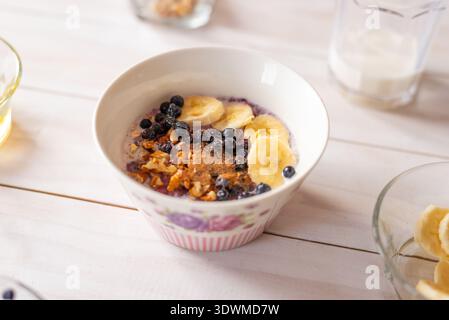 Hausgemachte Haferflocken mit Banane, Heidelbeeren, Walnüssen und Honig serviert in Keramikschale, gesundes ausgewogenes Frühstückskonzept Stockfoto