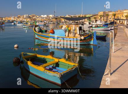 Farbenfrohe traditionelle Luzzu-Boote liegen im ruhigen Wasser des Hafens Marsaxlokk in Malta vor. Stockfoto