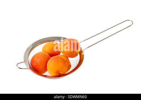 Frische reife Aprikosenfrüchte in Metallsieb isoliert auf weißem Hintergrund Stockfoto