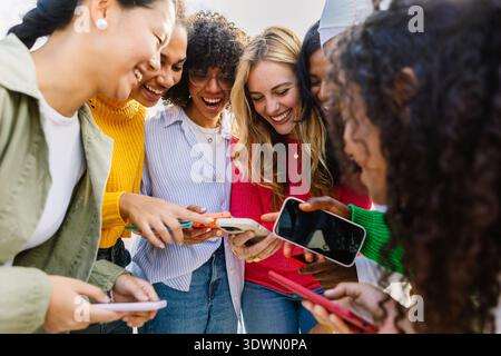 Gruppe weiblicher Freunde, die Spaß mit Mobiltelefonen im Freien haben Stockfoto