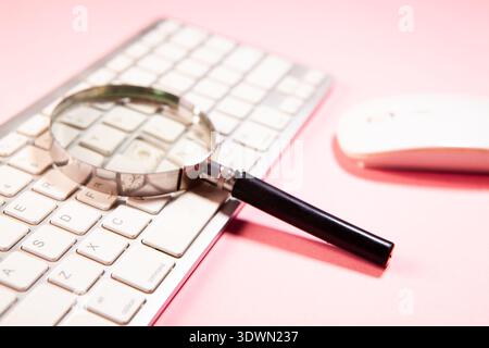 Die Lupe wird auf einer Computertastatur platziert. Stockfoto
