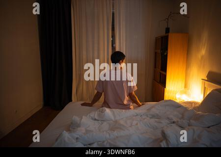 Schlaflose nachdenkliche Seniorin, die spät nachts im Bett sitzt und mit Schlaflosigkeit und Überdenken fertig wird. Stockfoto