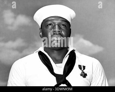 Dieses auffällige Schwarzweiß-Foto aus dem Jahr 1942 zeigt Doris 'Dorie' Miller, eine Mess Attendant Second Class in der US Navy, stolz auf das Navy Cross. Miller wurde für seinen Heldentum während des Angriffs auf Pearl Harbor geehrt, der sich durch die Besetzung einer Flugabwehrkanone auszeichnete, obwohl er keine vorherige Ausbildung hatte. Die Medaille ist auf seiner Uniform deutlich zu sehen, was sein mutiges Handeln symbolisiert. Stockfoto