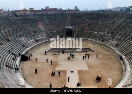 Panoramablick auf die antike Arena Verona, ein römisches Amphitheater in Italien, mit verwitterten Steinen, dem zentralen Arenaboden und einigen Besuchern Stockfoto