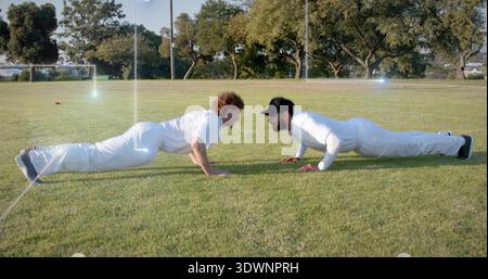 2 Cricketspieler in weißem Cricket-Kit, einer mit schwarzer Kappe auf Gras, orangefarbenem Kegel Stockfoto