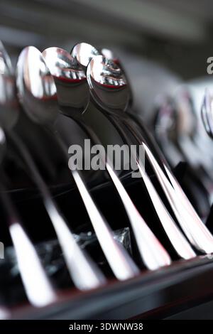 Glänzende Edelstahllöffel in einer Schublade angeordnet, Nahaufnahme mit reflektierenden Oberflächen, Küche Stockfoto