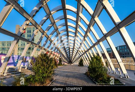 Saint-Denis, Frankreich - 29. Dezember 2025: Malerischer Blick auf die moderne Stahlkonstruktion, die Holzterrasse und die Landschaftsgestaltung der Fußgängerbrücke Franchissement Urbain Pleyel in der Nähe von Paris. Stockfoto