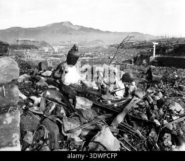 Dieses ergreifende Schwarz-weiß-Foto, das von CPL Lynn P. Walker Jr. im September 1945 aufgenommen wurde, zeigt zerschlagene religiöse Figuren mit Blick auf die verwüstete Landschaft von Nagasaki, Japan. Sechs Wochen nach dem Atombombenangriff veranschaulicht die Szene die weit verbreitete Zerstörung mit Trümmern, die sich über das Tal und die Berge in der Ferne erstrecken. Stockfoto