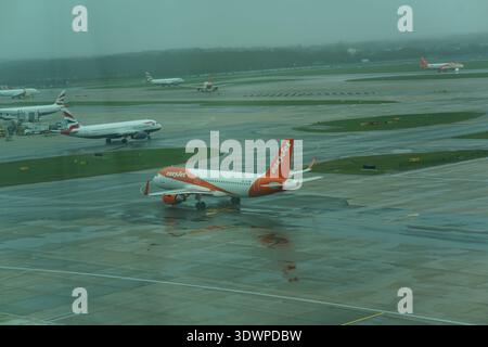 EasyJet Airbus auf dem regnerischen, nassen Vorfeld am Flughafen London Gatwick, Hintergrundflugzeugen und bewölktem Himmel, britische Luftfahrtszene. Stockfoto