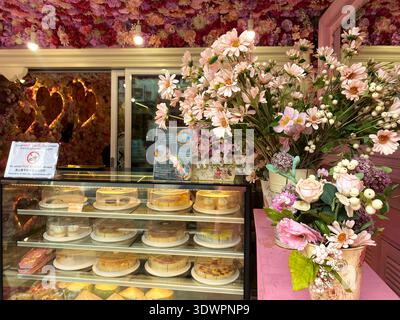 Phuket, Thailand - 28. Oktober 2025: Innenraum eines Süßwarengeschäfts mit einer Vitrine gefüllt mit verschiedenen Kuchen und einem Blumenarrangement Stockfoto