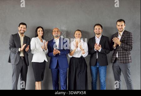 Lächelndes vielseitiges Business-Team applaudiert gemeinsam in modernen Unternehmensbüros Stockfoto