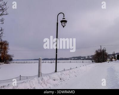 Winter im Lac Boivin in Granby, Quebec, Kanada. Schwimmende Brücke über den Fluss am Ende des Sees. Die Gegend um das Touristeninformationsbüro ist Popula Stockfoto