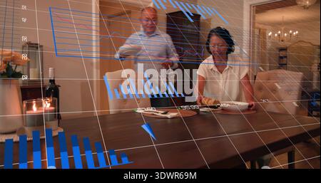 Karaffe gießen, reifer Mann und ältere Frau sitzen zu Hause am Esstisch, mit holografischen Karten Stockfoto
