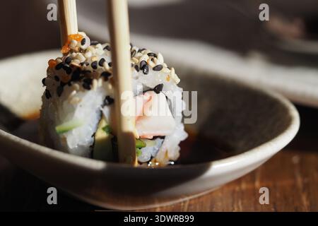 Sushi serviert mit Stäbchen in einer kleinen Schüssel Stockfoto