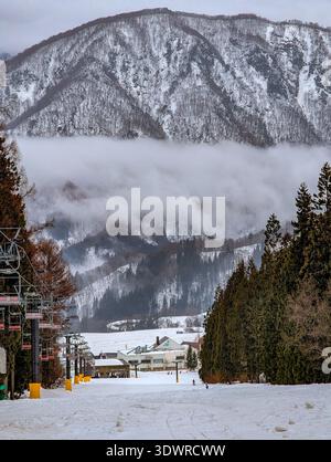 Winterskipiste in Norikura, Japan, mit Sesselliften und dramatischem Bergnebel Stockfoto