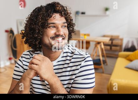 Junger Indianer, der wegschaut und am Schreibtisch lächelt Stockfoto