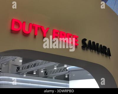 Duty-Free-Ladeneingangsschild mit beleuchtetem rotem Schriftzug über modernem Reiseeinzelhandelsbereich für Flughafenbeschilderung. Stockfoto
