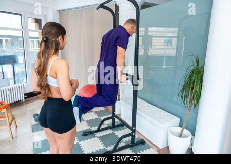 Ein Mann, der mit einem Therapeuten Dips an parallelen Balken durchführt Stockfoto