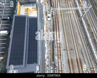 Aus der Vogelperspektive verlaufende Bahngleise parallel zu einem Gebäude mit Solarpaneelen im Kontrast zu industrieller und nachhaltiger Industrie, Karuizawa, Nagano, Japan. Stockfoto