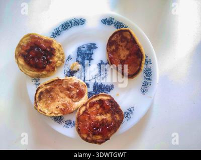 Ein Top-down-Schuss von vier goldenen Pfannkuchen mit Fruchtmarmelade. Dieses Bild in einem sonnendurchfluteten Budapester Haus repräsentiert das authentische häusliche Leben, Heilung Stockfoto