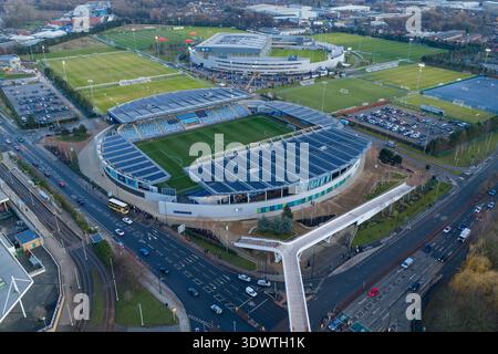 Luftbild des Etihad Campus in Manchester bei Sonnenuntergang mit dem Joie Stadium und der Fußgängerbrücke über den Alan Turing Way. Stockfoto