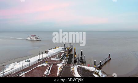 Blick aus der Vogelperspektive auf die Fähre, die bei Sonnenuntergang am Hafen ankommt Stockfoto