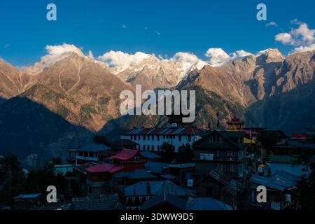 Dieser Blick auf Kalpa zeigt den traditionellen hölzernen Narayan-Nagini Tempel und Dorfhäuser vor dem schneebedeckten Kinnaur Kailash in der Ferne Stockfoto