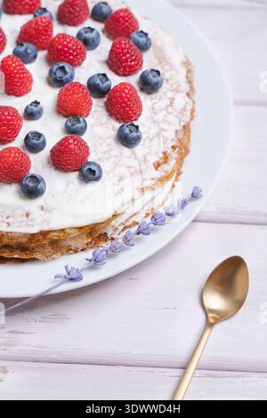 Runder Kreppkuchen gefüllt mit Sahne, gekrönt mit Himbeeren und Heidelbeeren, zart geschichteter Kuchen mit Sahnefüllung Stockfoto
