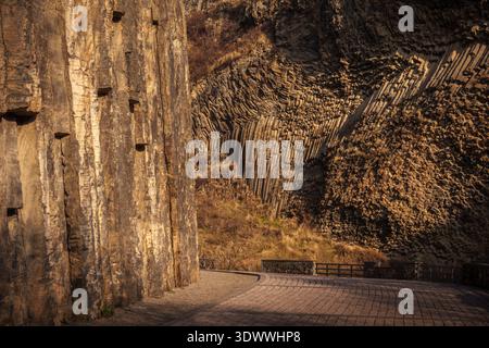 Garni, Armenien - 12 21 2025: Ein gepflasterter Wanderweg, der sich durch die Garni-Schlucht schlängelt, flankiert von hohen Mauern aus natürlichen Basaltsäulenformationen. Stockfoto