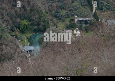 Abchasien, New Athos - 14. Februar 2026: Aus der Vogelperspektive auf den Bahnhof Psyrtskha und die kleine Kirche in der Nähe des türkisfarbenen Teichs, umgeben von bewaldeten Hügeln Stockfoto