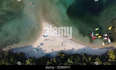 Blick von oben auf die Bella Vraka Sandbank, Sivota. Drohnenaufnahme von Sonnenschirmen, Kajaks und Paddelbrettern im flachen türkisfarbenen Wasser des Ionischen Meeres. Stockfoto